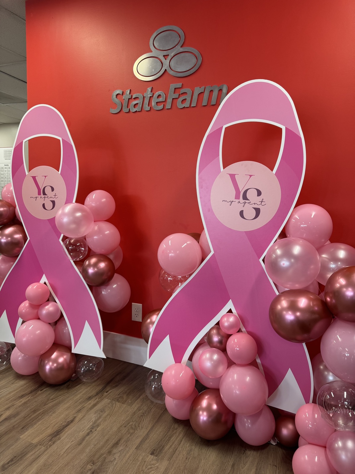 Pink October ribbon displays and pink balloon clusters under the State Farm sign at a South Florida agency